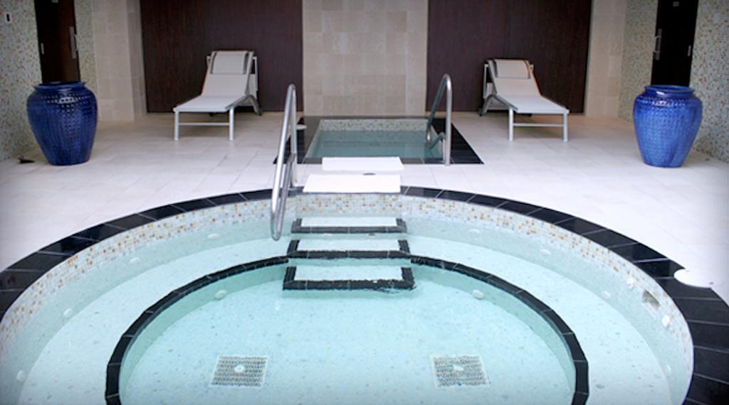 Hard Rock Hotel & Casino בילוקסי מראה חיצוני תמונה The photo shows a spa area featuring a circular hot tub or jacuzzi, surrounded by a black stone border. There are steps leading into the water, and the interior of the tub appears to be tiled. In the background, there are two white lounge chairs posi