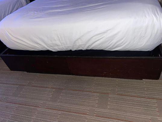 Hard Rock Hotel & Casino בילוקסי מראה חיצוני תמונה The photo shows a bed with a white mattress and bedsheet. The bed frame is dark-colored wood, and there is a storage compartment or drawer visible underneath the bed. The flooring appears to be a patterned carpet. The overall setting seems to be a be
